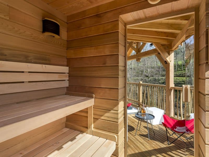 Sauna en bois avec vue sur la nature, espace détente extérieur confortable.