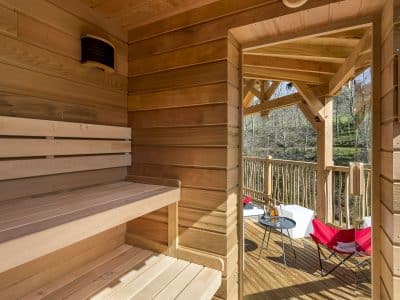 Sauna en bois avec terrasse, offrant une vue apaisante sur la nature en Auvergne-Rhône-Alpes.