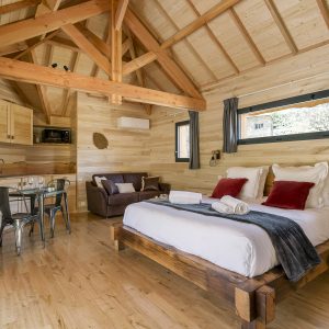 Chalet en bois chaleureux avec lit king-size et cuisine ouverte, situé en Auvergne-Rhône-Alpes.