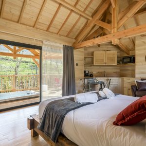 Chalet en bois avec vue sur la nature et jacuzzi sur la terrasse.