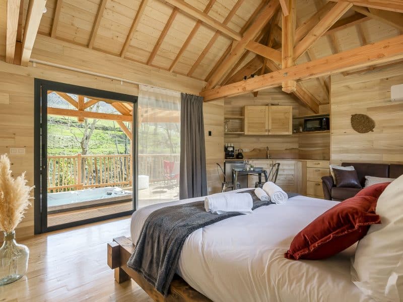 Chalet en bois avec vue sur la nature et jacuzzi sur la terrasse.
