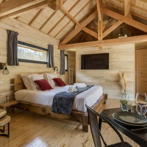 Chalet en bois moderne avec lit douillet et décoration chaleureuse en Auvergne-Rhône-Alpes.