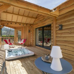 Cabane en bois avec jacuzzi sur la terrasse, vue sur la nature en Auvergne-Rhône-Alpes.