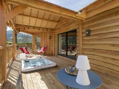 Cabane en bois avec jacuzzi sur la terrasse, vue sur la nature en Auvergne-Rhône-Alpes.