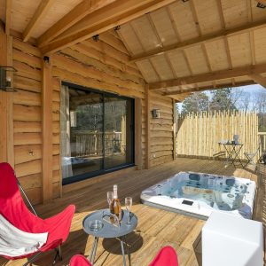 Cabane en bois avec jacuzzi sur la terrasse, idéale pour un séjour relaxant.