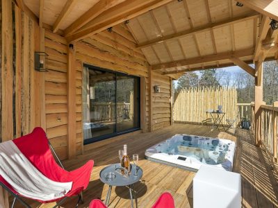 Cabane en bois avec jacuzzi sur la terrasse, idéale pour un séjour relaxant.