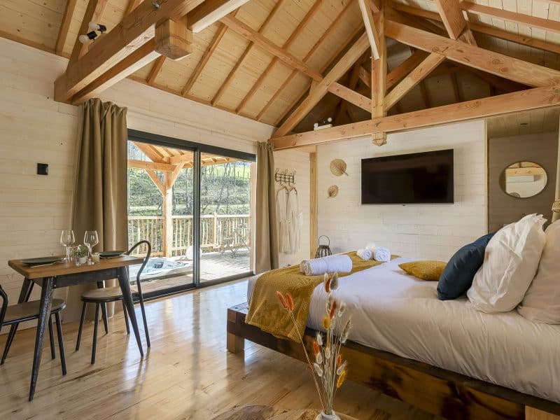 Chalet en bois avec plafond en poutres, vue sur la terrasse et décoration chaleureuse.