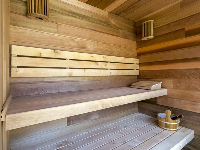 Sauna en bois chaleureux avec bancs en bois et éclairage doux. Détente assurée.