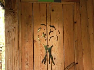 Cabane en bois avec une porte sculptée dun arbre, située en Bourgogne-Franche-Comté.