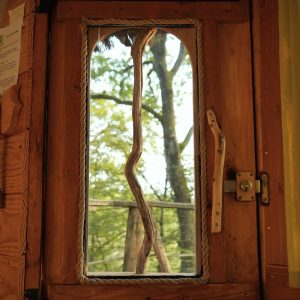 Vue dune fenêtre en bois dun hébergement insolite en Bourgogne-Franche-Comté, entouré darbres.