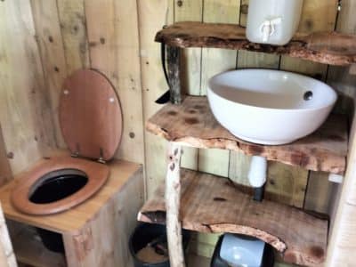 Hébergement insolite en Bourgogne-Franche-Comté avec toilettes en bois et lavabo en pierre.