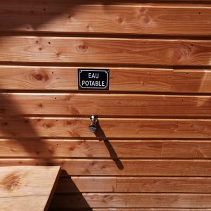 Cabane en bois en Auvergne-Rhône-Alpes avec robinet deau potable visible.