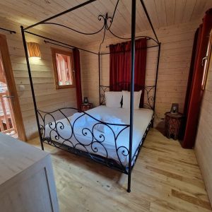 Chalet en bois avec lit à baldaquin et décor chaleureux en Aquitaine.