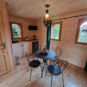 Hébergement insolite en Aquitaine : chalet en bois avec table ronde et lampes colorées.