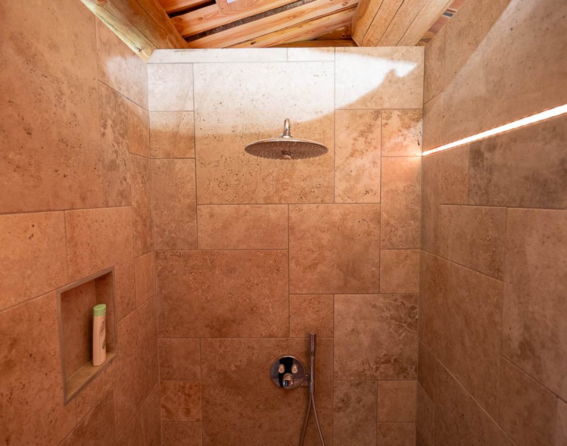 Douche en pierre dans un hébergement insolite à Champagne-Ardenne, ambiance naturelle.