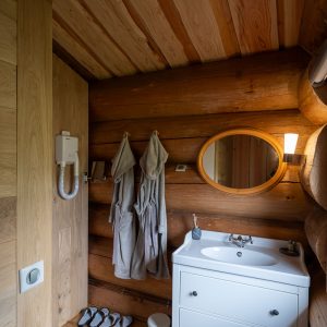 Hébergement insolite en bois à Champagne-Ardenne, avec salle de bain moderne et miroir rond.