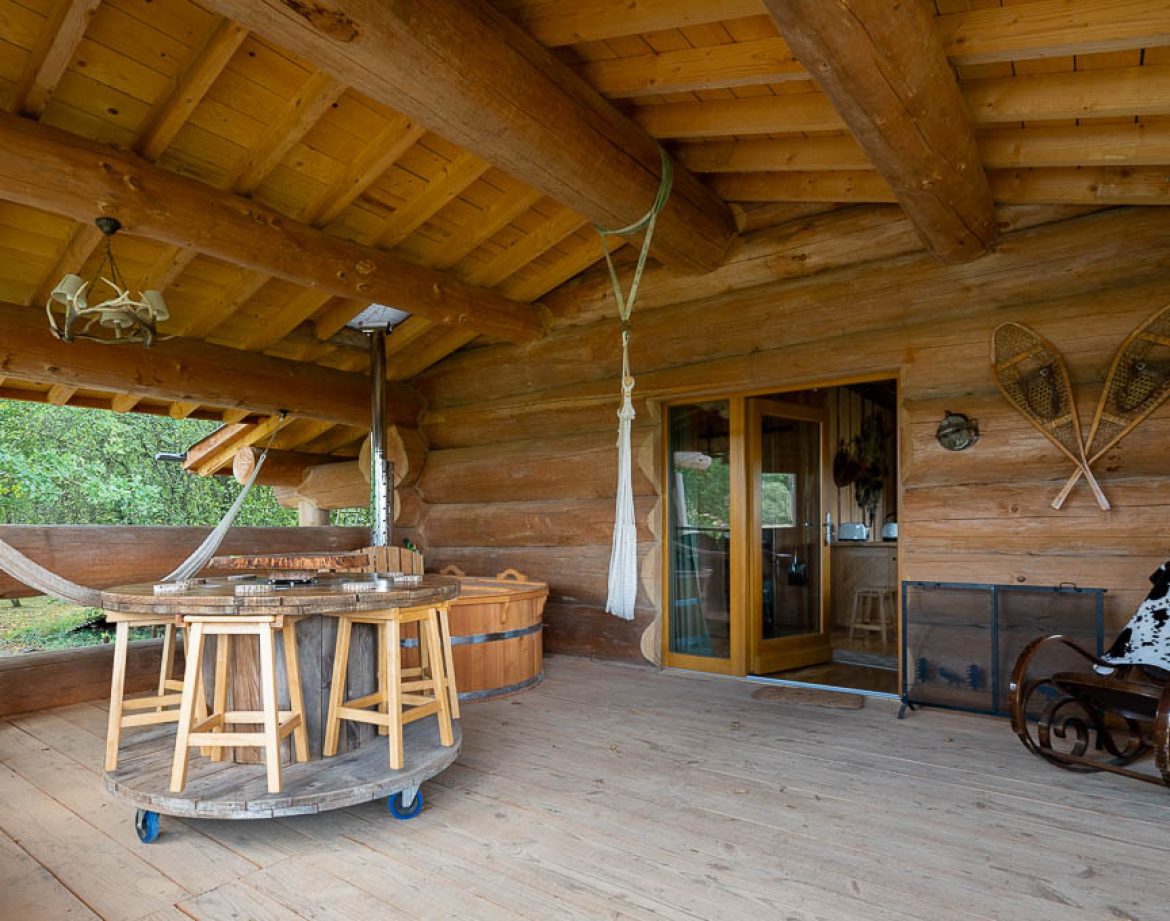 Hébergement insolite en rondins avec terrasse en bois et hamac accueillant.