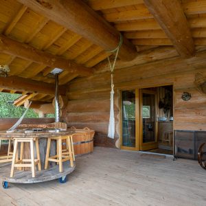 Hébergement insolite en rondins avec terrasse en bois et hamac accueillant.