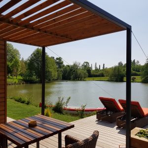 Hébergement insolite en Aquitaine : chalet moderne avec vue sur le lac et transats.