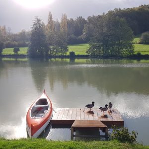 Hébergement insolite en Aquitaine, avec un canoë orange sur un lac paisible.