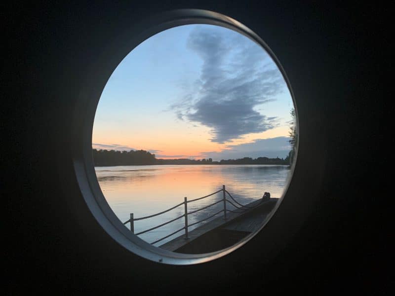Cabane flottante avec vue circulaire sur un coucher de soleil paisible.