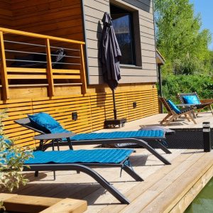 Hébergement insolite en Aquitaine : chalet moderne avec terrasse surplombant un étang.