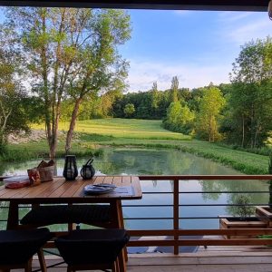 Cabane sur pilotis en Aquitaine avec vue sur un étang et la verdure environnante.