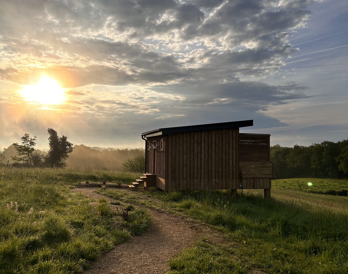 Cabane en bois au coucher de soleil, entourée de verdure en Aquitaine.