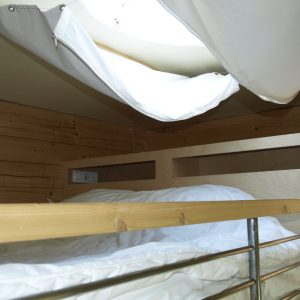 Cabane perchée en Midi-Pyrénées avec lit en bois et fenêtre lumineuse.