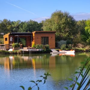 Cabane flottante en Aquitaine, au bord dun lac paisible, entourée de verdure.