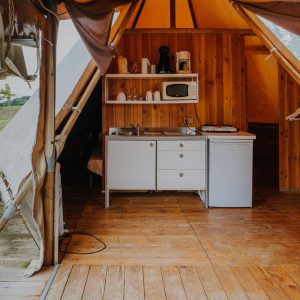 Tente lodge spacieuse en Midi-Pyrénées, avec kitchenette en bois et ambiance chaleureuse.
