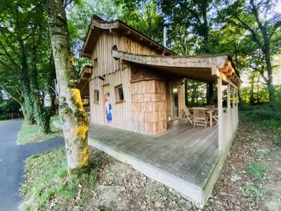 Cabane en bois en Bretagne, entourée darbres, avec terrasse en bois accueillante.