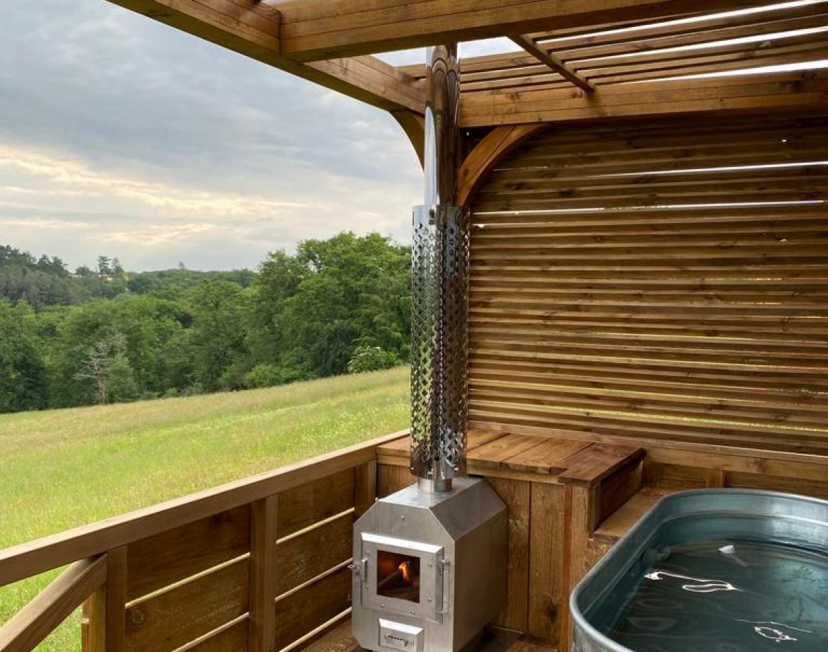 Hébergement insolite en Aquitaine : cabane en bois avec poêle et baignoire en métal.