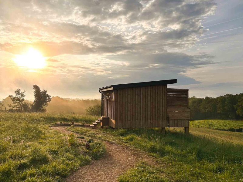 Cabane en bois surélevée, baignée par la lumière dorée du coucher de soleil.