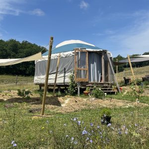 Yourte spacieuse en pleine nature, entourée de fleurs et de verdure.