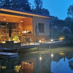 Cabane flottante en Aquitaine, illuminée au bord dun étang paisible.