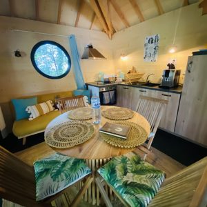 Cabane en bois en Bretagne, avec un coin cuisine et une grande fenêtre ronde.