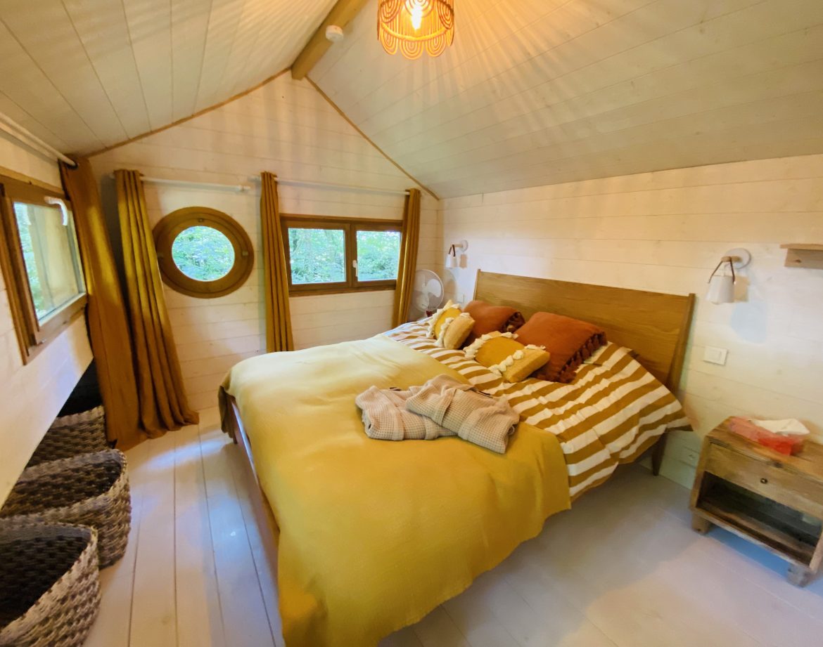 Chalet cosy en Bretagne, avec un lit douillet et des rideaux dorés.