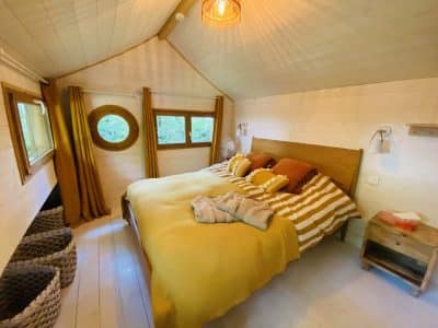 Chalet cosy en Bretagne, avec un lit douillet et des rideaux dorés.