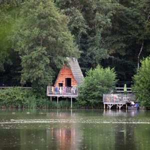 Cabane en bois au bord dun lac, entourée de verdure luxuriante en Auvergne-Rhône-Alpes.