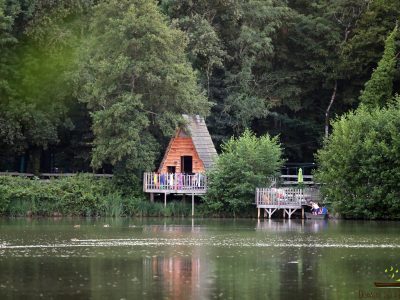 Cabane en bois au bord dun lac, entourée de verdure luxuriante en Auvergne-Rhône-Alpes.