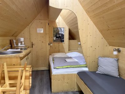 Chalet en bois chaleureux avec lit confortable et coin cuisine, ambiance cocooning.