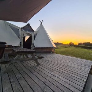 Tipi en Midi-Pyrénées avec terrasse en bois, vue sur un coucher de soleil.