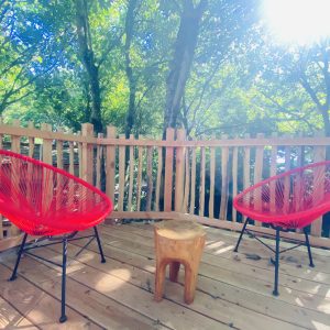 Hébergement insolite en Bretagne : deux chaises rouges sur une terrasse boisée.