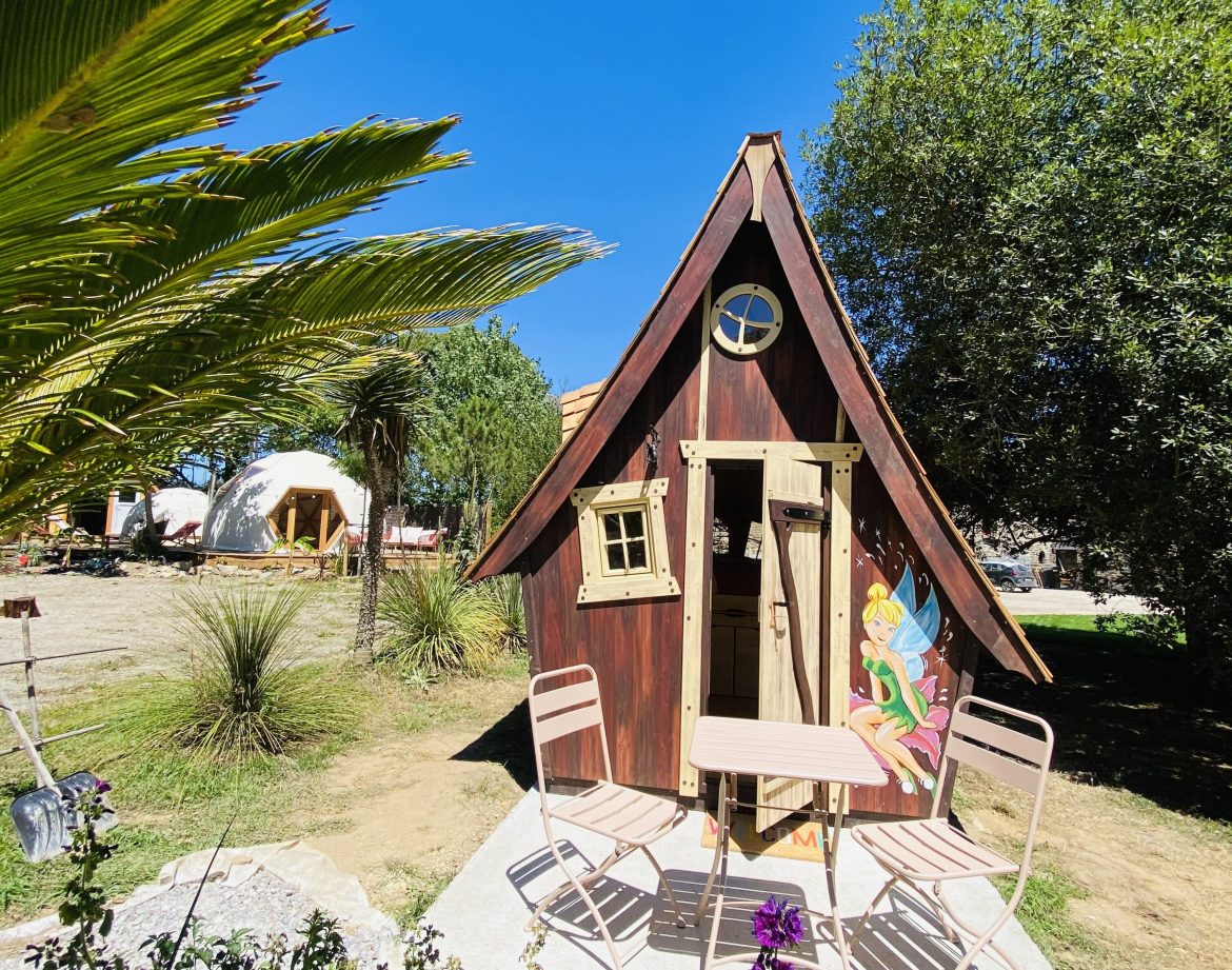 Cabane en bois colorée en Bretagne, avec table et chaises sur la terrasse ensoleillée.