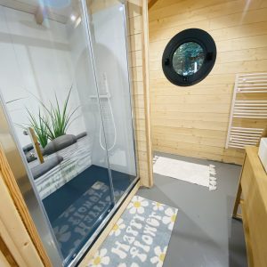 Cabane en bois en Bretagne avec douche moderne et décoration florale.
