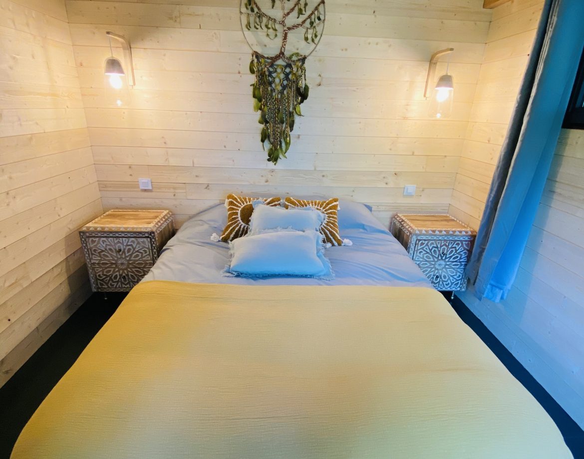 Chalet en bois avec lit douillet et décoration bohème, situé en Bretagne.