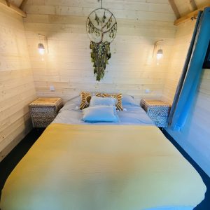 Chalet en bois avec lit douillet et décoration bohème, situé en Bretagne.