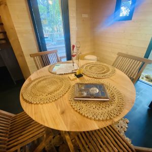 Hébergement insolite en Bretagne : chalet en bois avec table ronde et chaises en rotin.