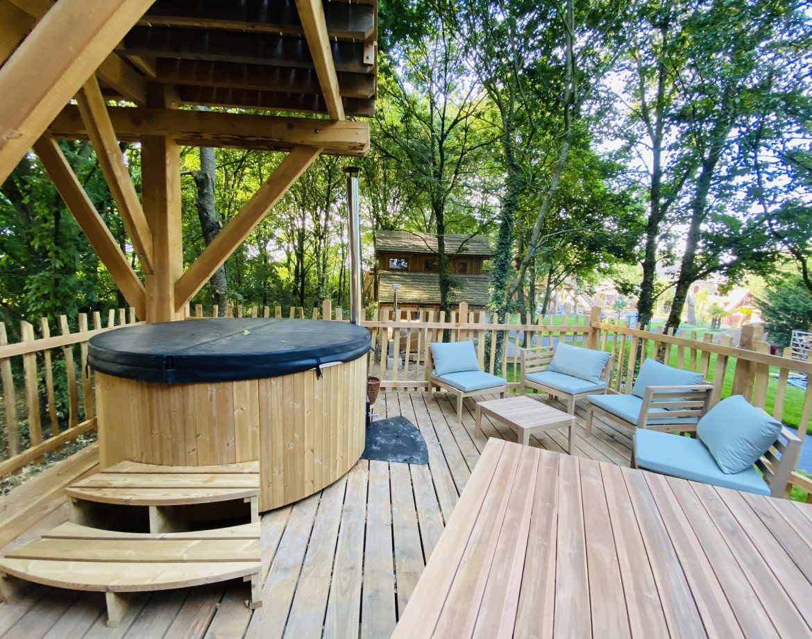 Hébergement insolite en Bretagne : cabane en bois avec jacuzzi et coin salon en extérieur.